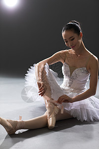 坐着纯洁舞蹈青年女人整理芭蕾舞鞋背景图片