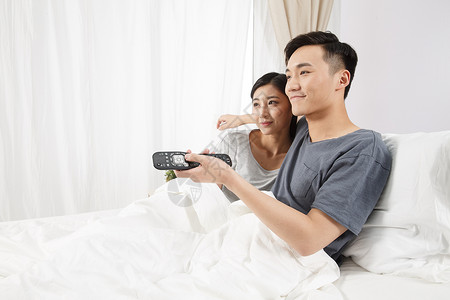 男朋友快乐青年情侣坐着床上看电视图片