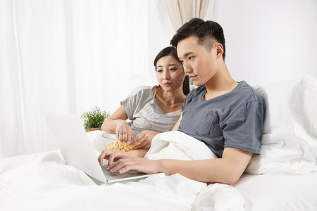 起居室便利女人青年情侣坐着床上看电脑图片