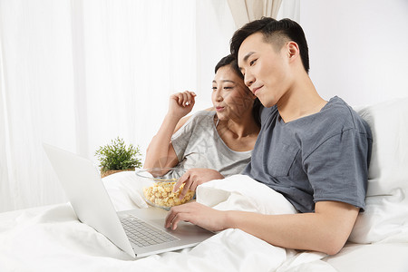 乐趣亚洲人温馨青年情侣坐着床上看电脑图片