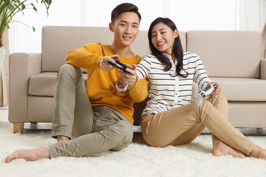 异恋坠入爱河亚洲人青年情侣坐着沙发上玩游戏图片