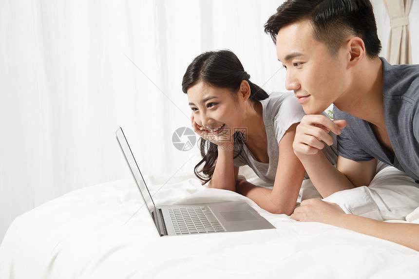 互联网半身像和谐青年情侣趴在床上看电脑图片