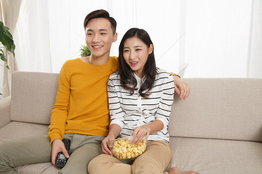 女朋友高兴的愉悦青年情侣坐着沙发上看电视图片