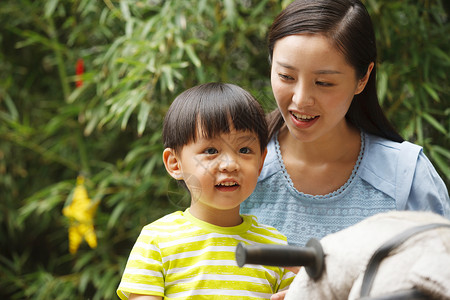 小孩骑木马玩耍幼儿园学童两个人幼儿园里老师和男孩在户外背景