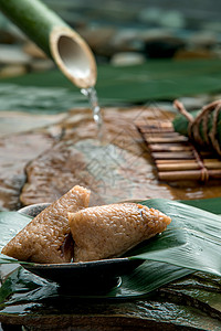 盛水竹筒小溪流水边的肉粽背景