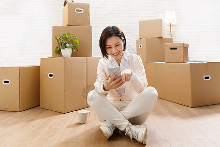 智能住宅坐着住宅房间智能手机青年女人看手机背景