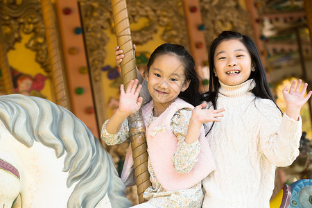 游乐园玩耍微笑两个小女孩在玩旋转木马图片