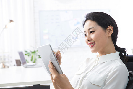 办公桌自信轻松办公青年商务女人使用平板电脑办公图片
