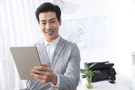 满意互联网户内青年商务男人拿着平板电脑办公图片