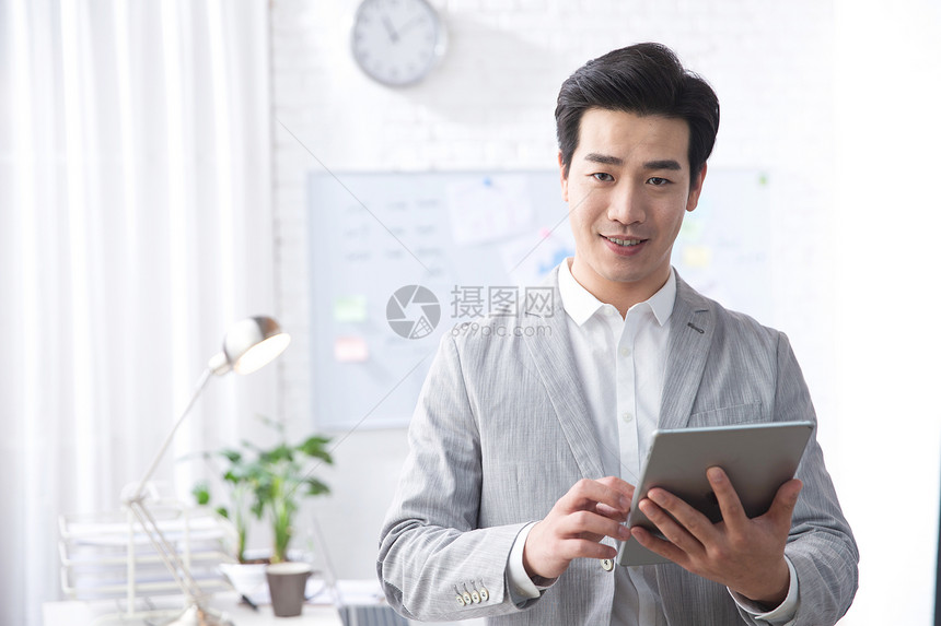 活力户内轻松青年商务男人拿着平板电脑办公图片