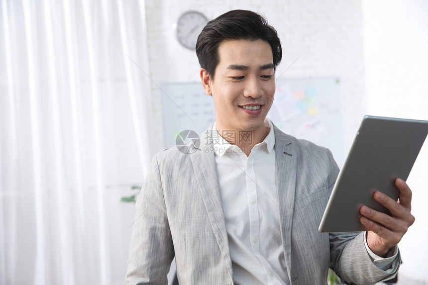 职业办公桌着装得体青年商务男人拿着平板电脑办公图片