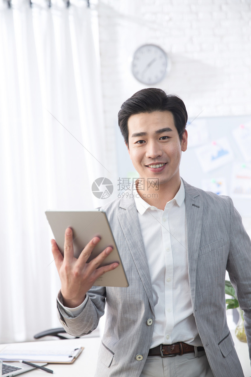 青年商务男人拿着平板电脑办公图片