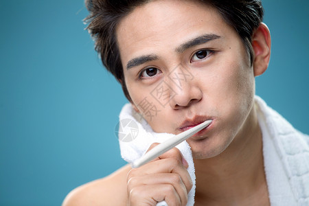 年轻男人用毛巾擦刷牙时脸上的泡沫高清图片