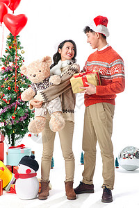 抱着圣诞树的熊树传统节日帽子快乐的青年情侣过圣诞节背景