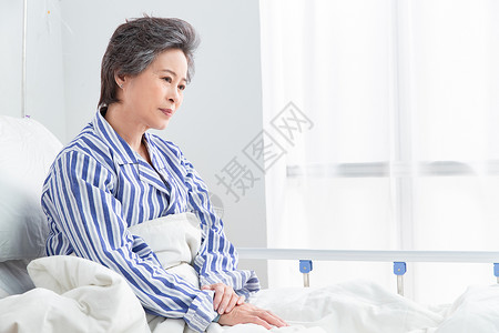 悲哀50多岁病房老年患者坐在医院病床上背景图片