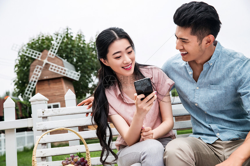 男人女人青年伴侣坐在户外看手机图片