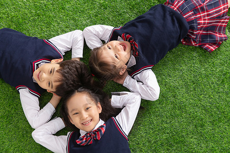 摄影亚洲智力小学生们躺在草地上图片