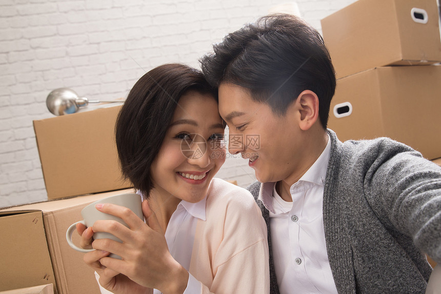 亚洲青年女人活力年轻夫妇坐在地板上喝水图片