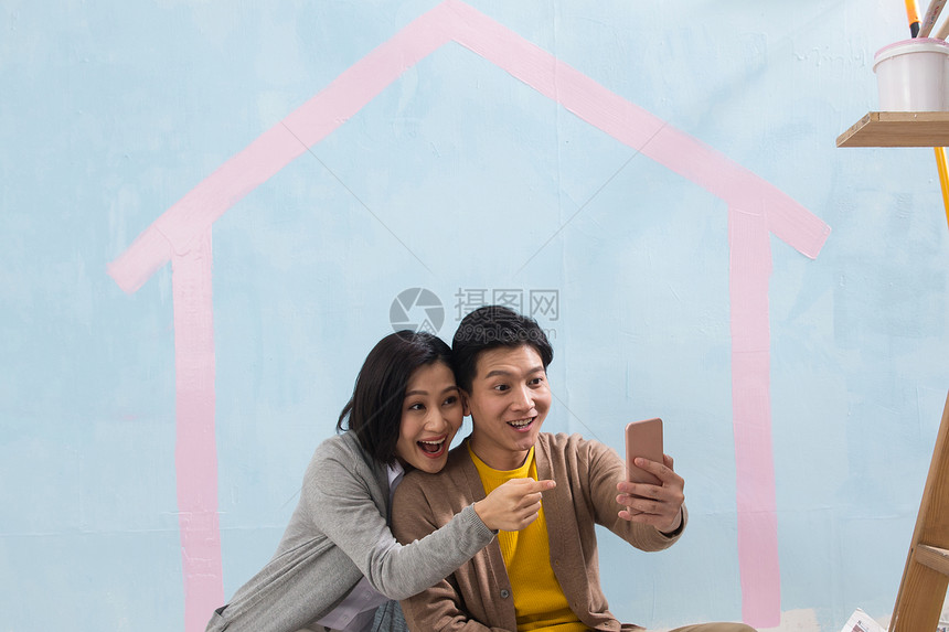 关爱房地产快乐年轻夫妇用手机拍照图片