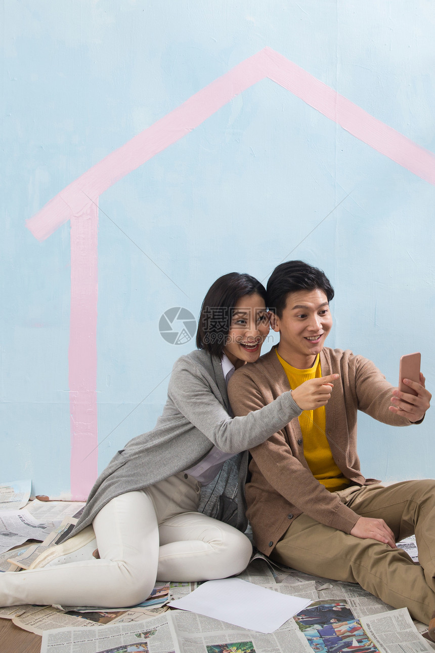 搂着起居室丈夫年轻夫妇用手机拍照图片