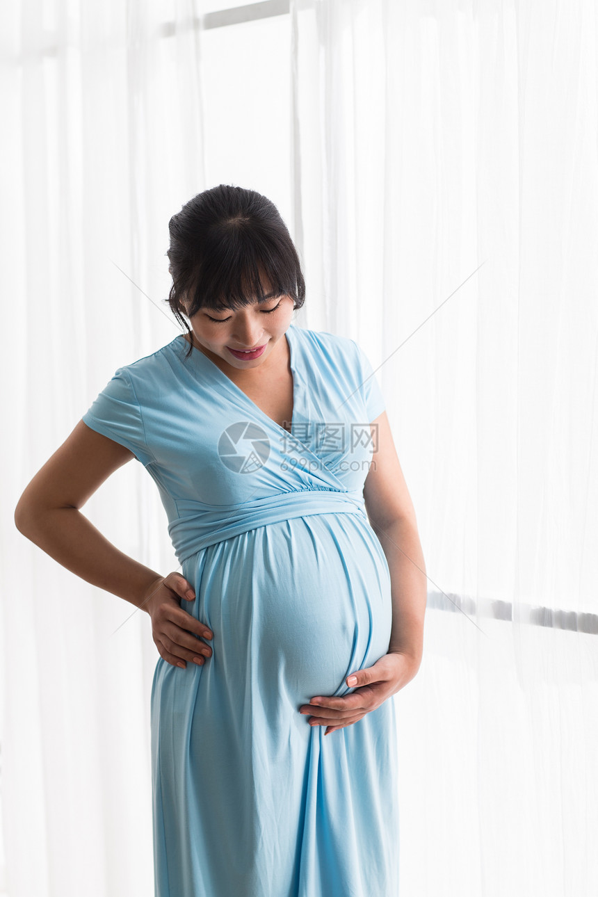 母亲手放在肚子上微笑幸福的孕妇图片