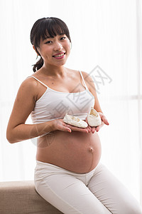 幸福的孕妇手拿婴儿小鞋子图片