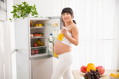 轻松拿证孕妇打开冰箱拿果汁背景