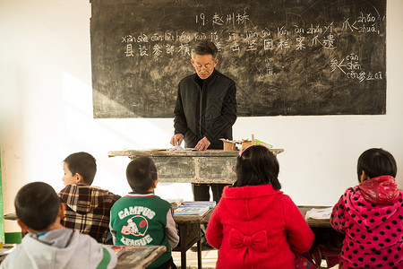 希望相伴逆境乡村男教师和小学生在教室里高清图片