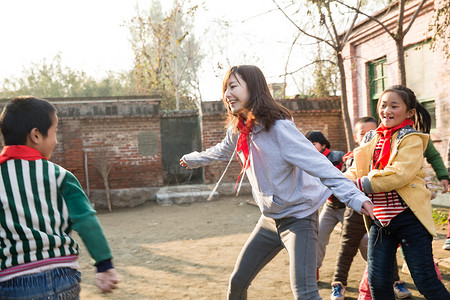 追赶玩耍的学生活力红领巾志愿者乡村教师和小学生在学校里做游戏背景