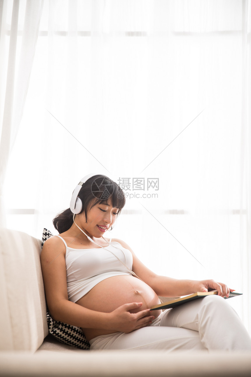 垂直构图简单人孕妇听音乐看书图片