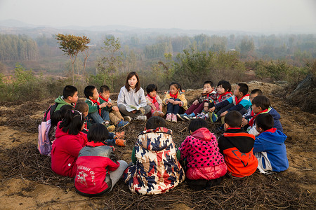 微笑的坐在地上读书乡村教师和小学生在户外学习图片