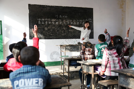 志愿者在行动男生课桌希望乡村女教师和小学生在教室里背景