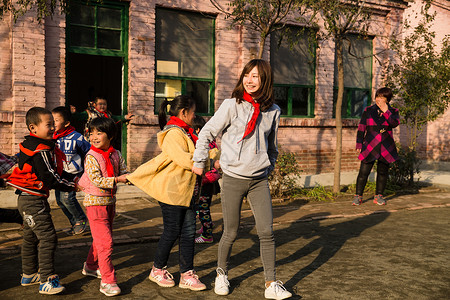 追赶玩耍的学生女人希望友谊乡村教师和小学生在学校里做游戏背景