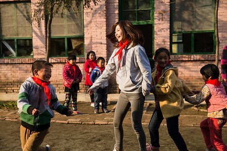 追赶玩耍的学生校园抓白昼乡村教师和小学生在学校里做游戏背景