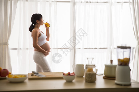 20多岁露出肚子杯子孕妇喝果汁高清图片