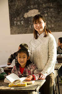 志愿者努力指导教师乡村女教师和小学生在教室里课桌高清图片素材