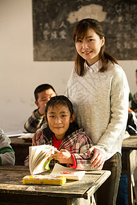 小学女生环境青年女人乡村女教师和小学生在教室里课桌高清图片素材