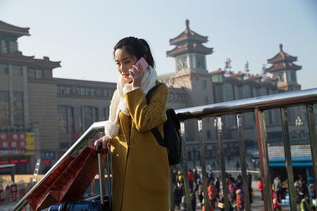 手机旅行拿着青年女人在站前广场背景图片