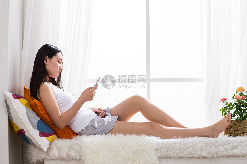放松短裤东方人青年女人在卧室用手机图片