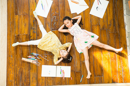 相伴无忧无虑可爱的姐妹俩躺在地板上玩耍图片