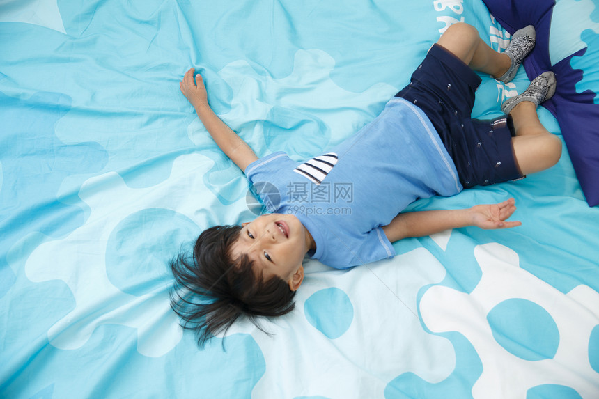 白昼仅一个人幸福可爱的小男孩在床上玩耍图片
