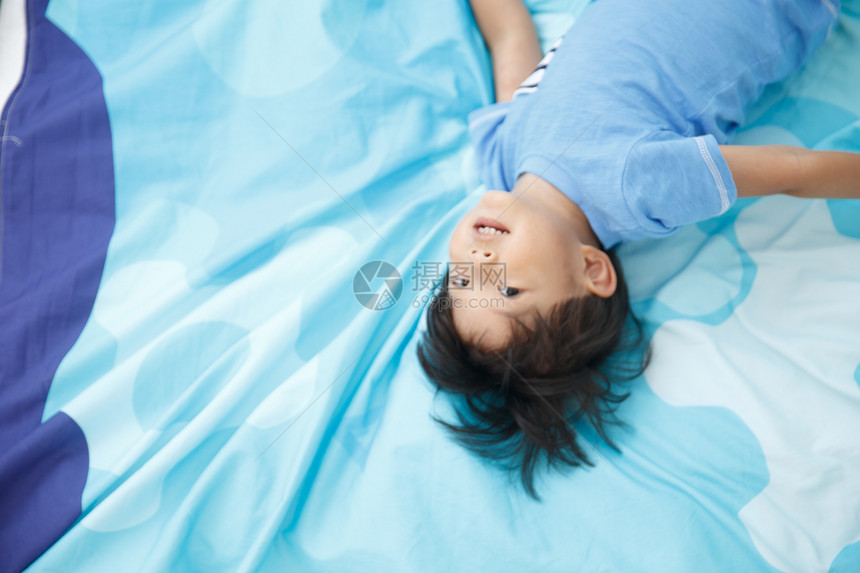 健康的住宅房间可爱的小男孩在床上玩耍图片