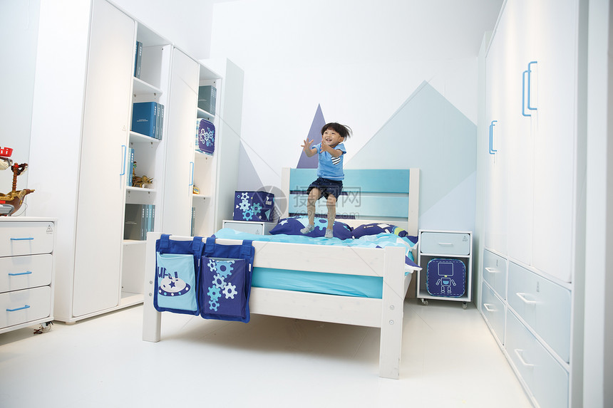 蓝色生长户内可爱的小男孩在床上玩耍图片