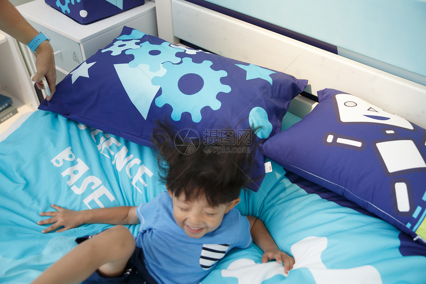 舒适休闲东方人可爱的小男孩在床上玩耍图片