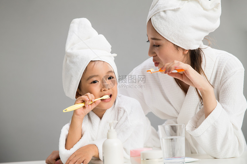 关爱青年女人微笑穿着浴袍的母女刷牙图片