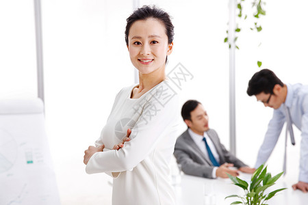 青年女人站着前景聚焦商务人士在办公室工作图片