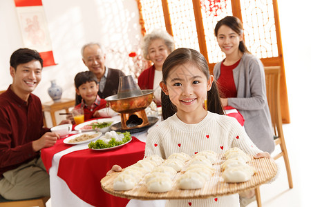 少量人群两个孩子的家庭快乐小女孩过年端着饺子节日高清图片素材