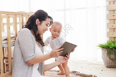 年轻妈妈和宝宝看平板电脑高清图片