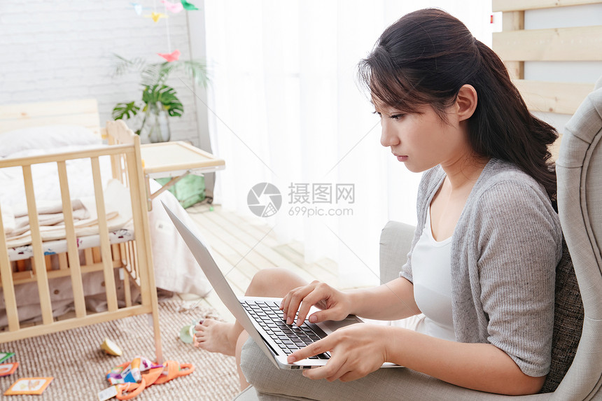 水平构图休闲坐着青年女人坐在沙发上使用笔记本电脑图片