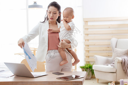 家庭生活烦躁商务年轻妈妈抱着孩子在家办公图片素材